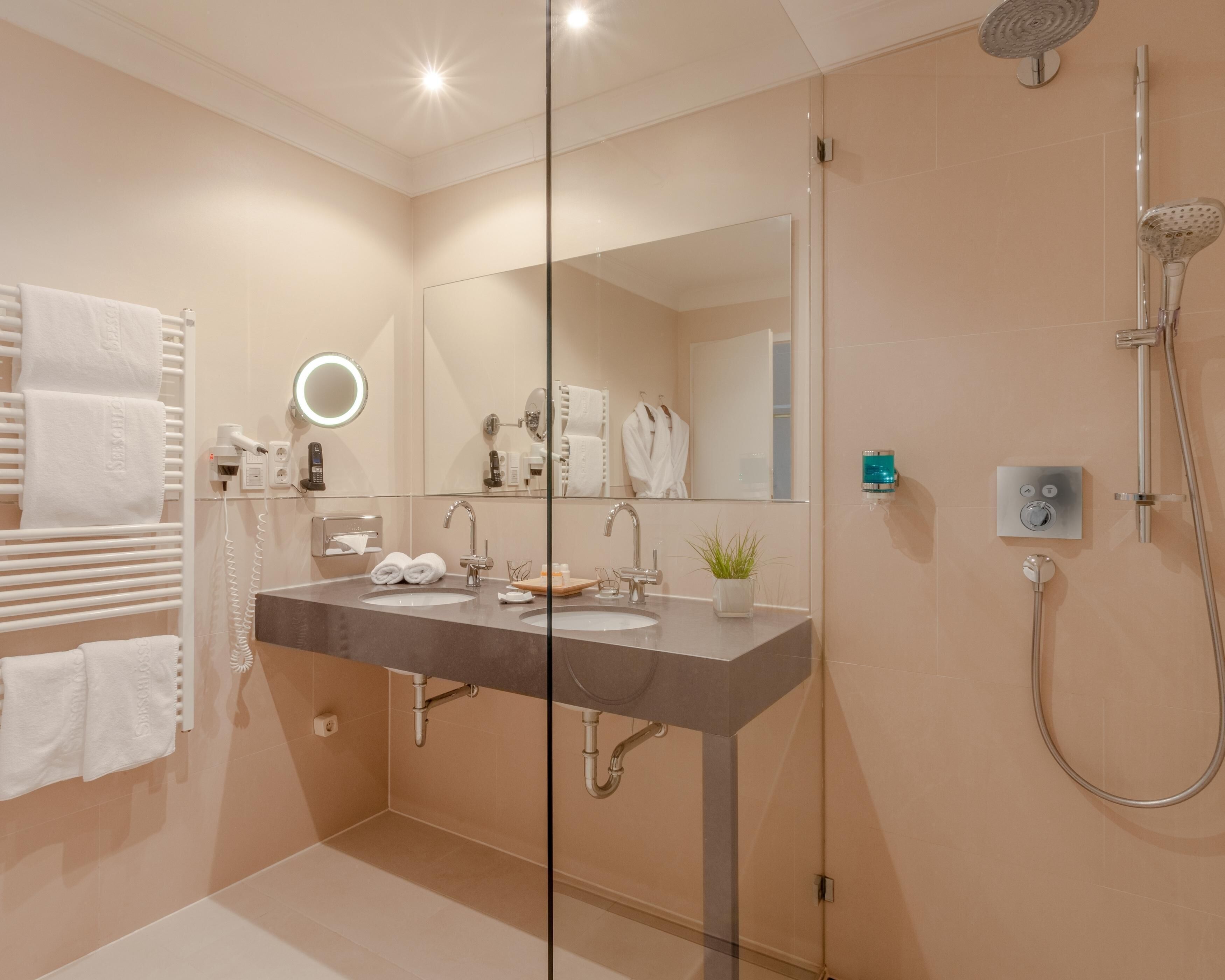 A modern bathroom with a dual sink vanity, a glass shower enclosure, and a towel rack with neatly folded towels.