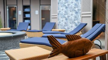 Un espace aménagé au bord de la piscine, avec des chaises longues, un jacuzzi et une sculpture décorative représentant un poisson.