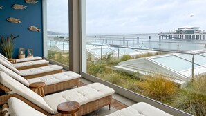 Un área de descanso moderna con mobiliario de mimbre y vistas a una marina costera.