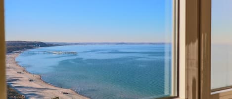 A coastal view with a beach, pier, and clear sky.