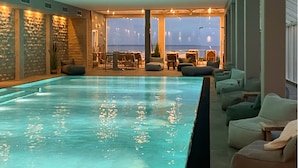 Zona de piscina con asientos y vistas al océano.