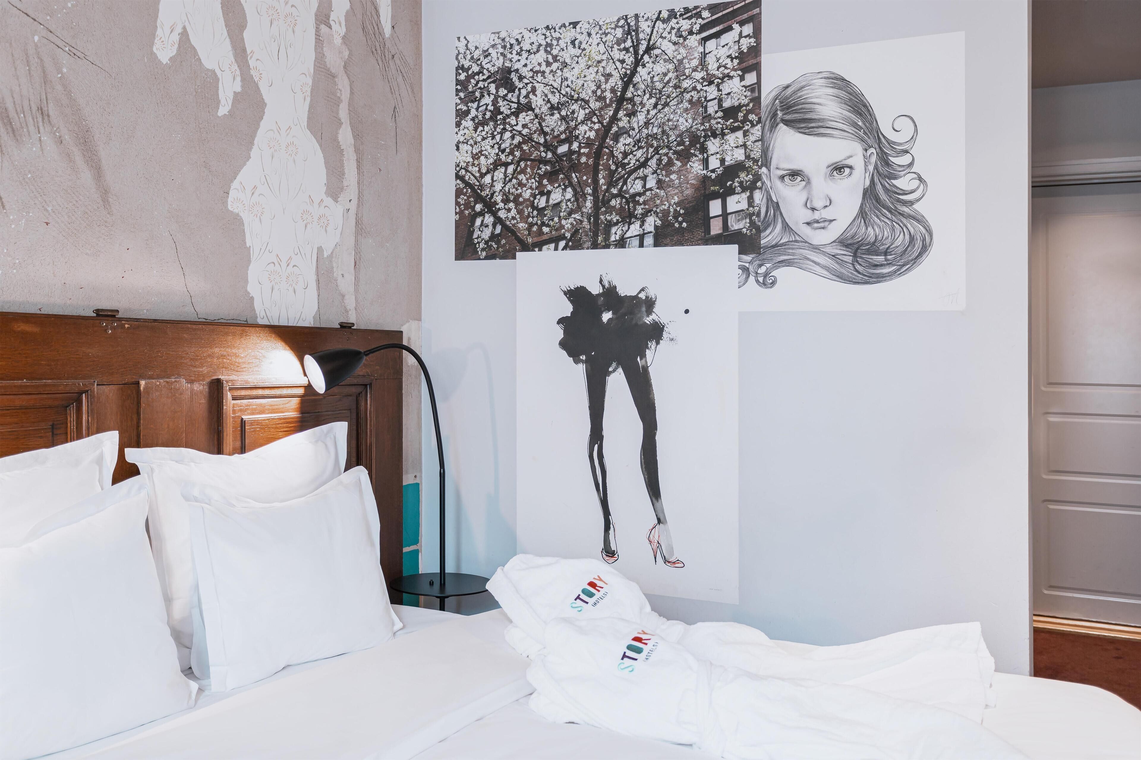 A hotel room with a wooden headboard, white bedding, and artwork on the walls.