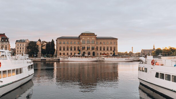 A large, historic building with a central dome, surrounded by calm water and moored boats. - STORY HOTEL STOCKHOLM STUREPLAN, in JdV by Hyatt (Stockholm)