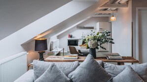 A cozy loft-style living space with a sloped ceiling, a dining area, and a kitchen in the background. - STORY HOTEL STOCKHOLM STUREPLAN, in JdV by Hyatt (Stockholm)