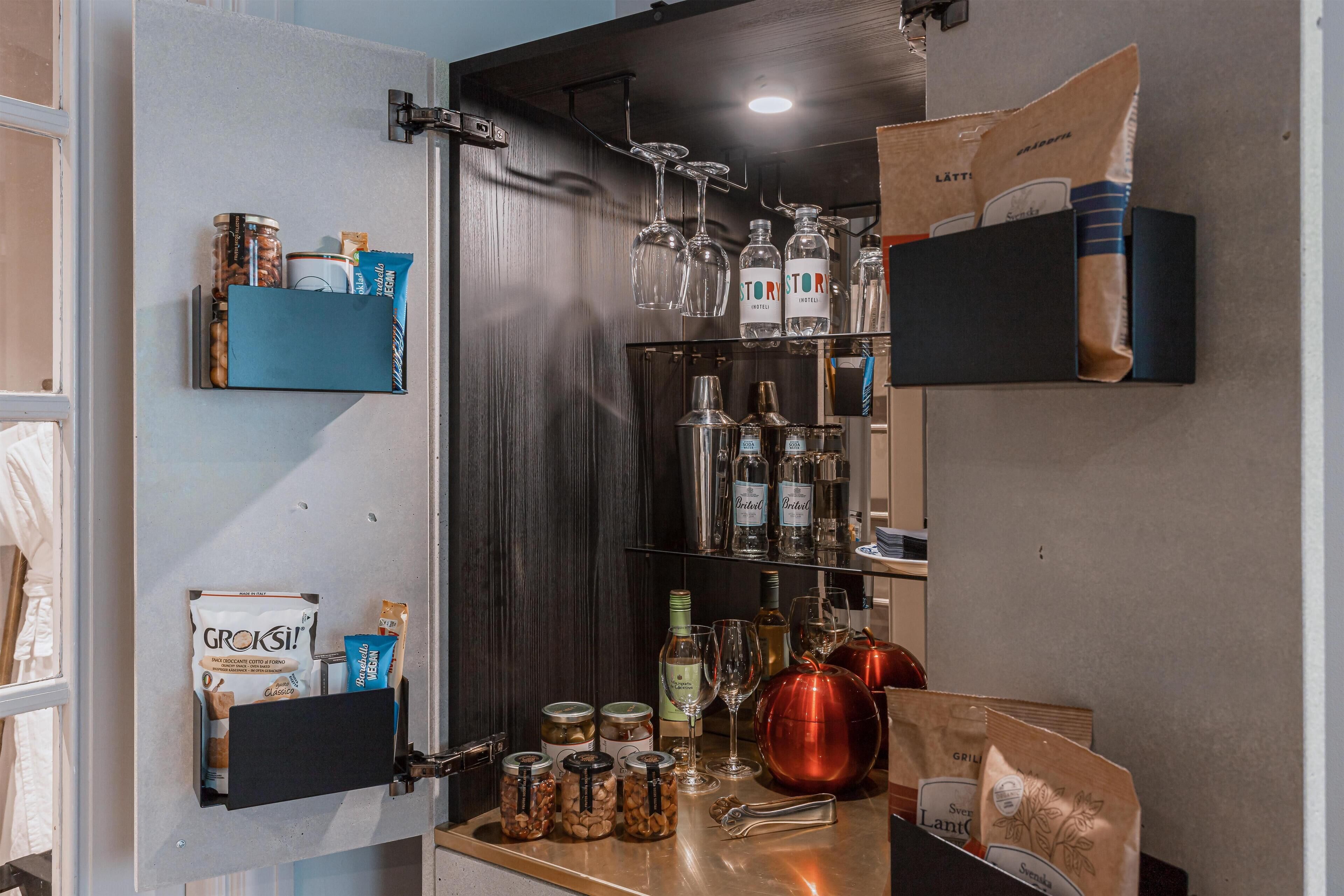 A bar area with shelves of liquor bottles, glasses, and jars of nuts.