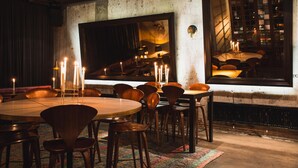 A dining area with a round table, multiple chairs, candles, and a large mirror on the wall. - STORY HOTEL STOCKHOLM STUREPLAN, in JdV by Hyatt (Stockholm)