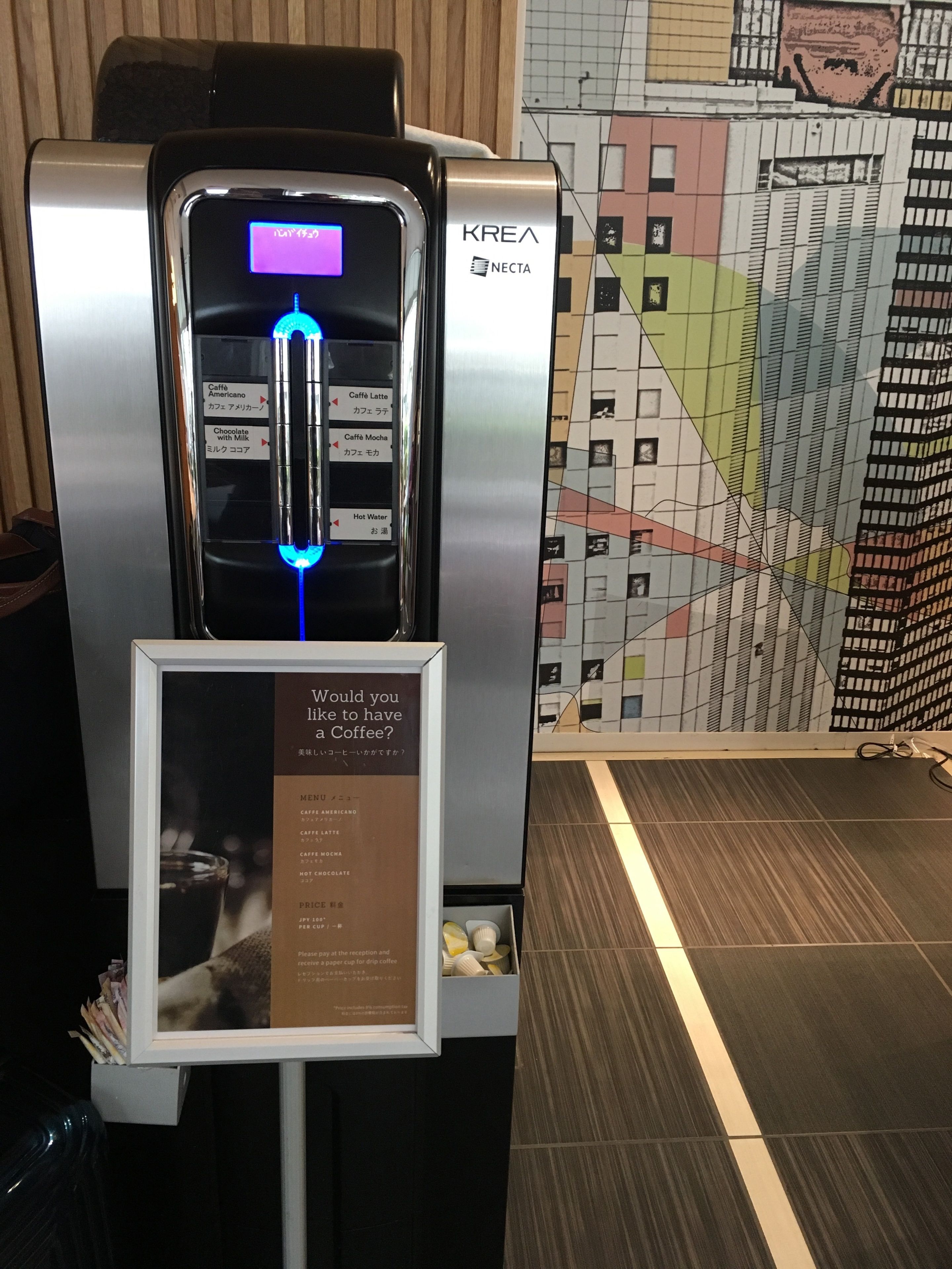 En kaffemaskine med digitalt display og menutavle der viser kaffevarianter.