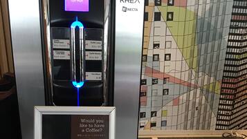 En kaffemaskine med digitalt display og menutavle der viser kaffevarianter.