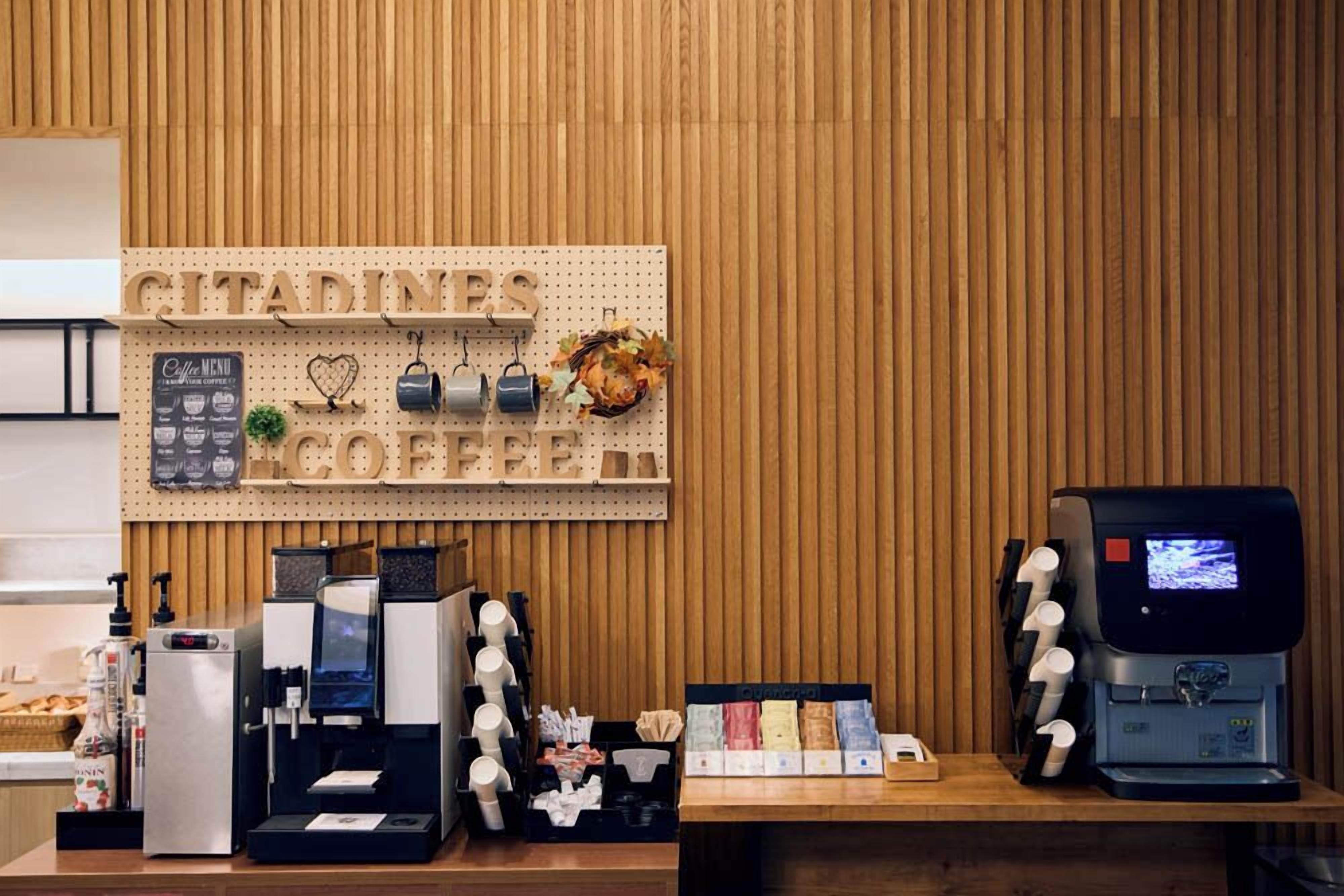 A coffee shop counter with a coffee menu, espresso machines, and a display of coffee cups.