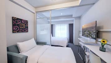 A modern hotel room with a large bed, a desk, a chair, a TV, and a painting on the wall.