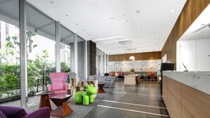 A modern interior with a reception desk, seating area, and a view of the outdoors. - Citadines Shinjuku Tokyo (Tokyo)