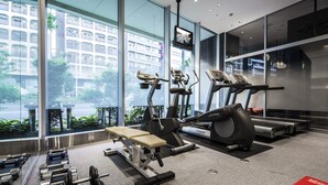 A modern gym with exercise equipment, large windows, and a view of a cityscape. - Citadines Shinjuku Tokyo (Tokyo)