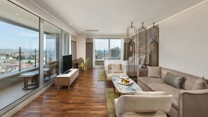 A spacious living area with a large window, a sofa set, a dining table, and a TV. - Titanic Port Bakirkoy (Istanbul)