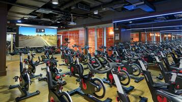 A gym with multiple stationary bikes arranged in rows.