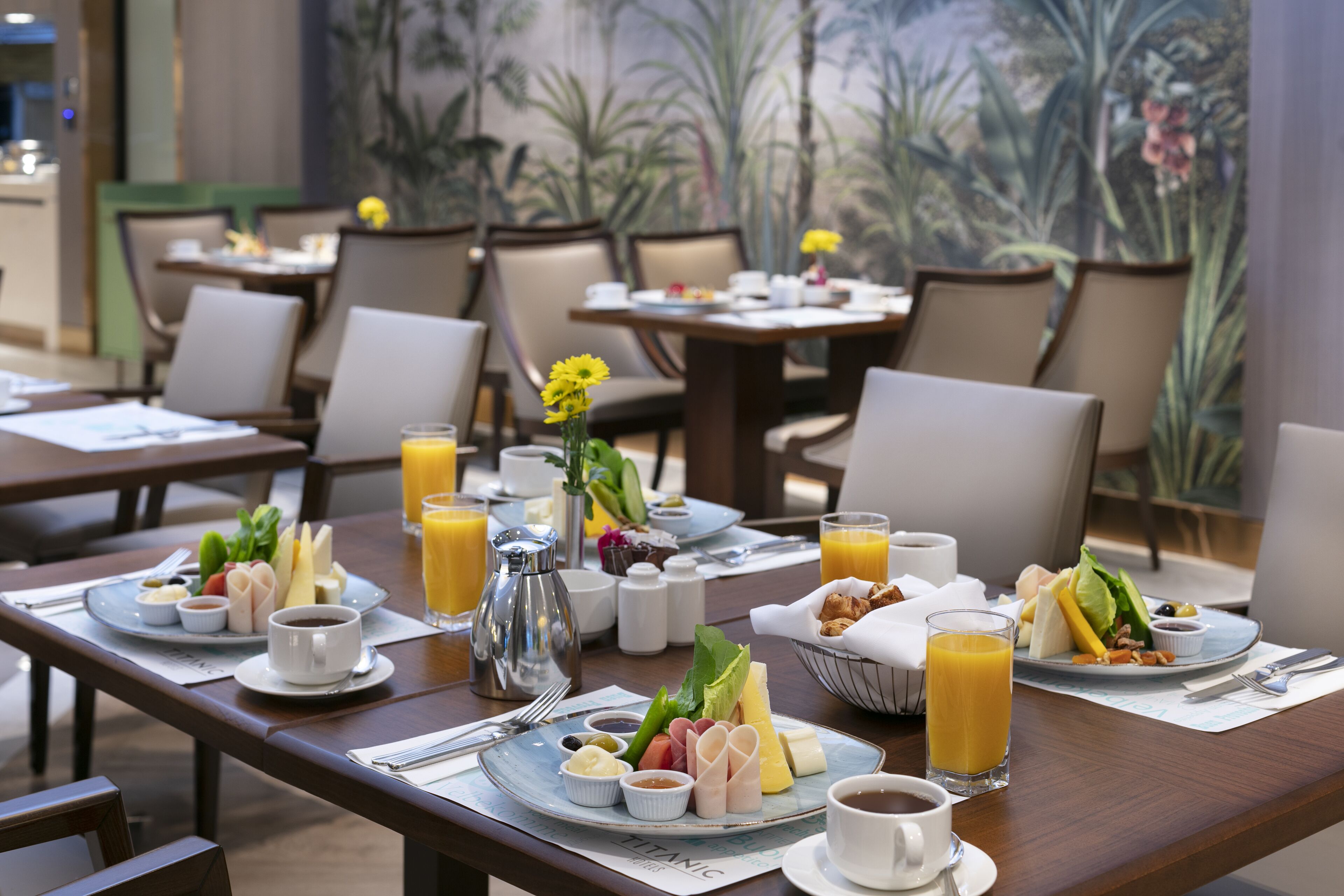 Ein Frühstücksbuffet mit verschiedenen Speisen und Getränken, in einem Essbereich mit Stühlen und Tischen.