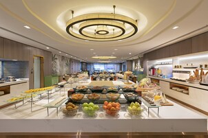 Un bufé de desayuno de hotel con una variedad de frutas, cereales y bollería.