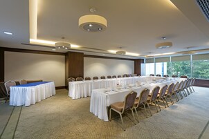 Una sala conferenze con un lungo tavolo, sedie e luci a soffitto.