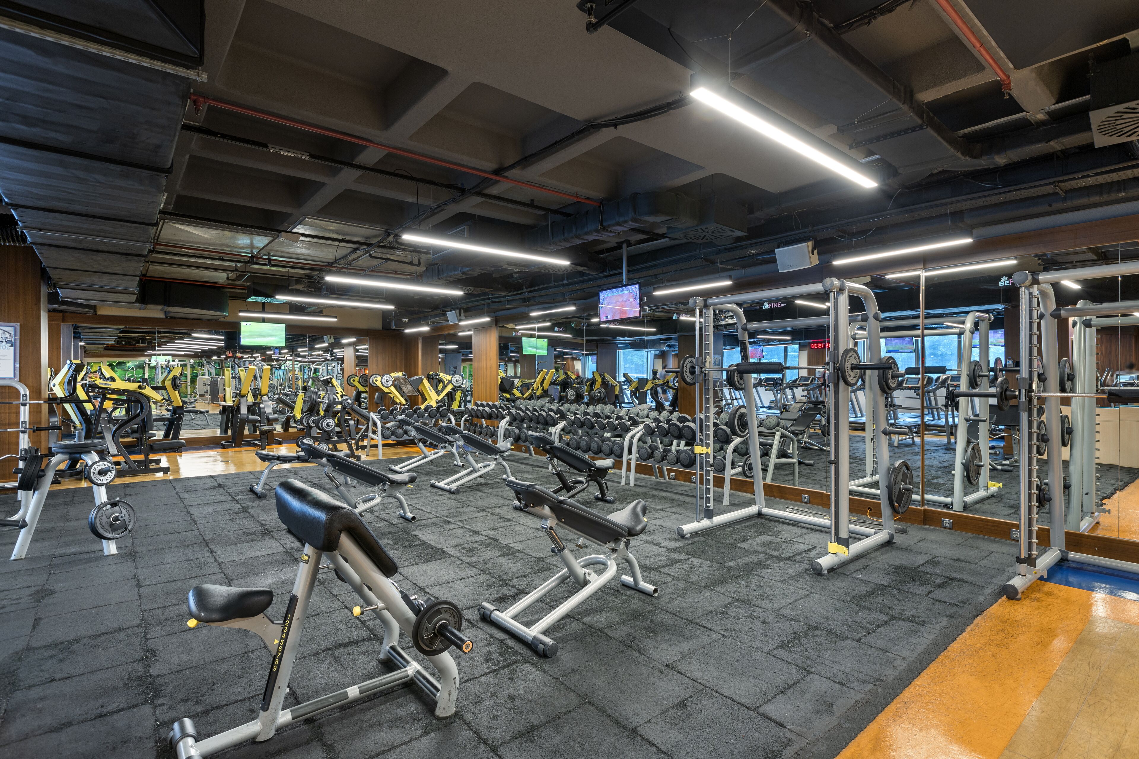 A gym with various exercise equipment, including treadmills, weight machines, and dumbbells.