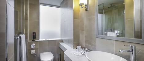 A modern bathroom with a large mirror, a white sink, and a toilet.