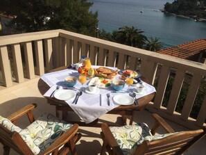 A table set for breakfast on a balcony overlooking a coastal area with a view of the sea and boats. - Captain's Villa Sokol (Lumbarda)