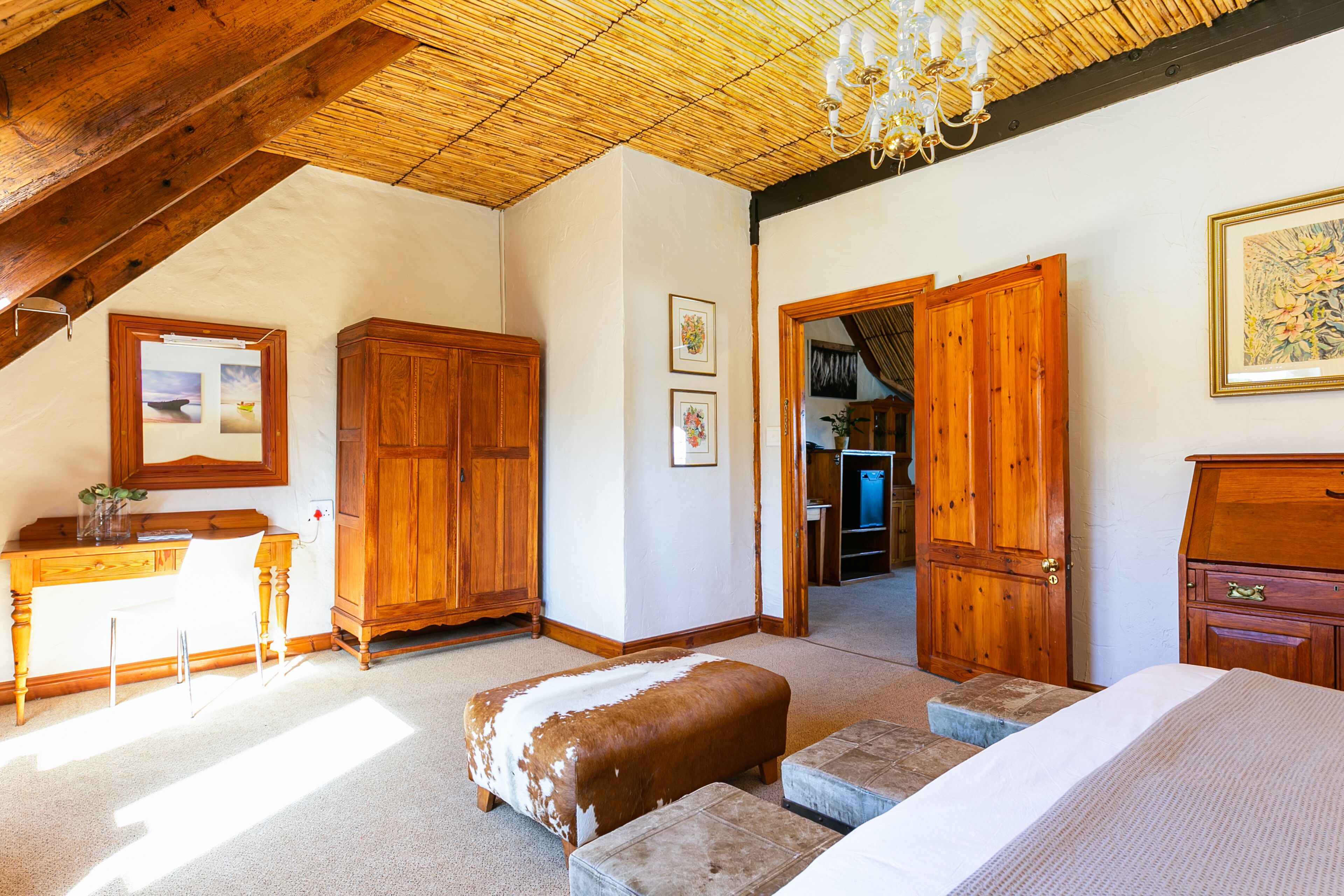 Una camera da letto con soffitto in legno, un letto, una scrivania e un armadio.