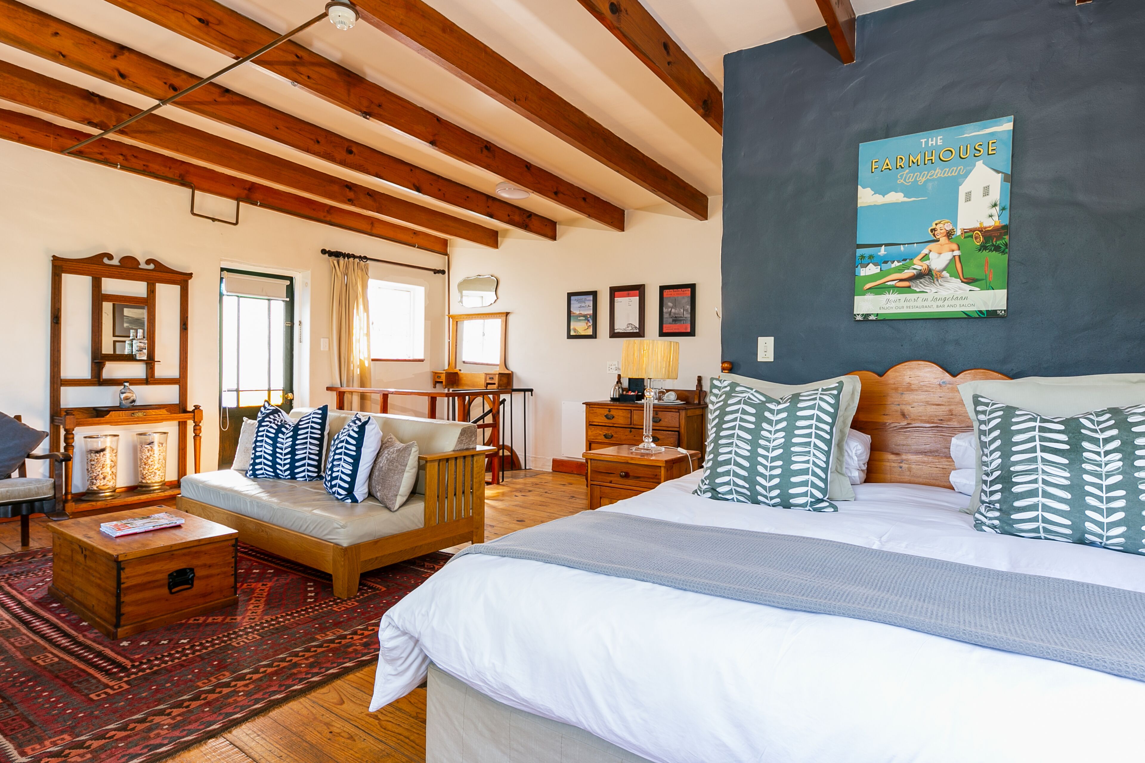 A spacious room with a large bed, a sofa, a wooden coffee table, and a desk.