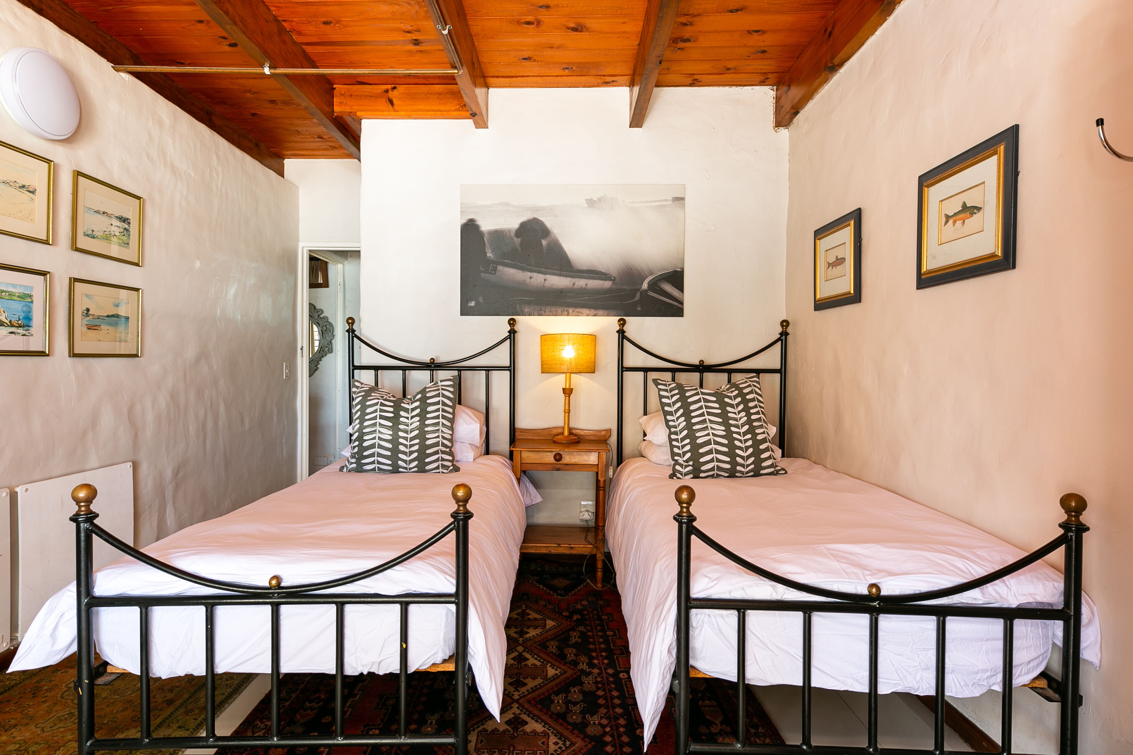 A room with two beds, a wooden ceiling, and a framed picture on the wall.
