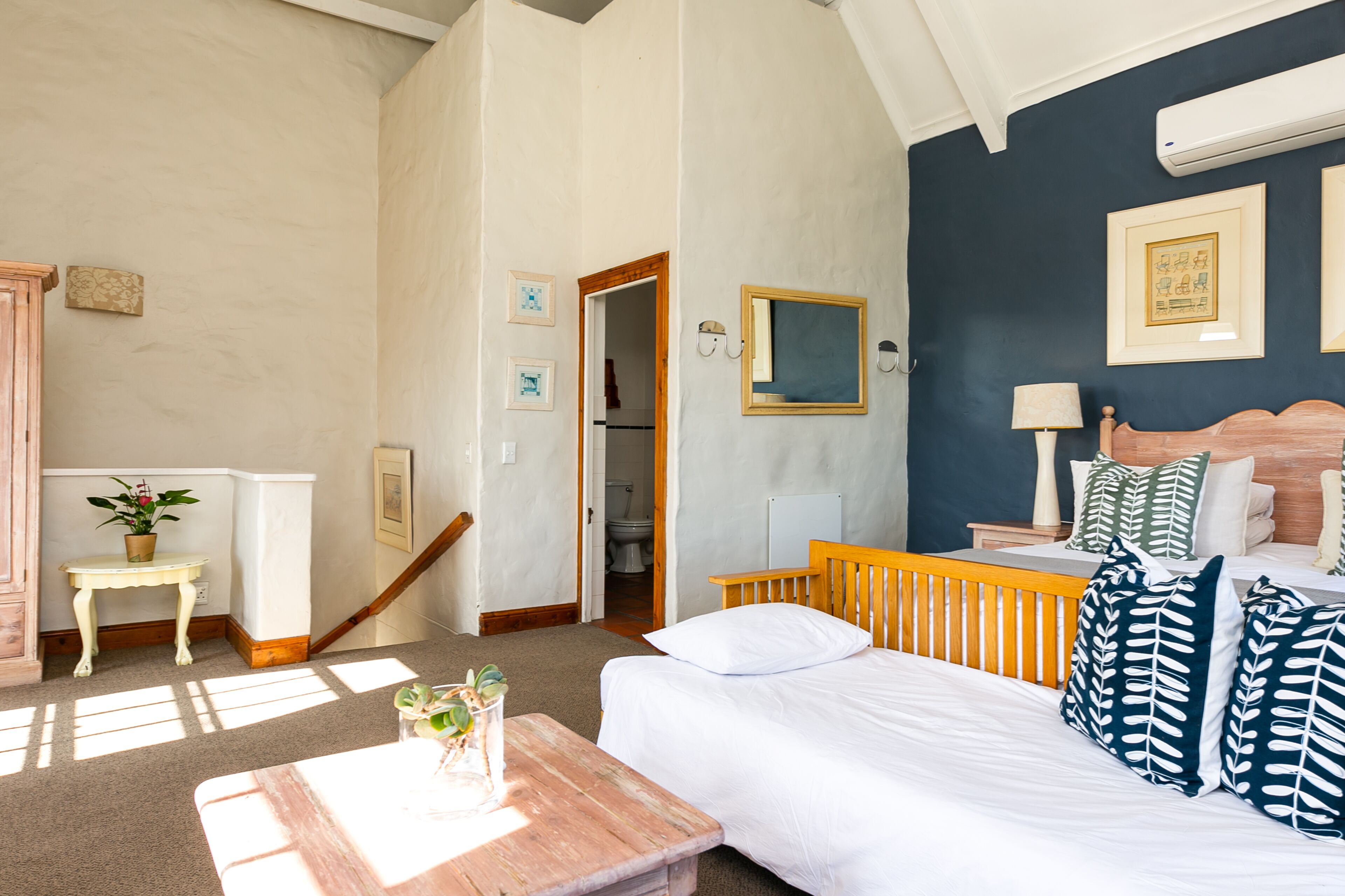 A bedroom with a bed, bedside table, and a view of the bathroom.