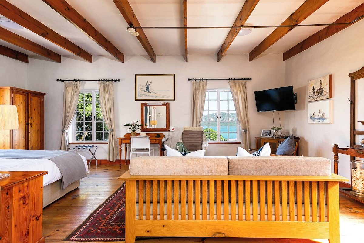 A room with a wooden bench, a bed, a desk, a chair, and a television.