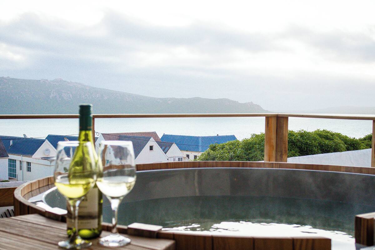 A hot tub with a view of houses and mountains in the background.
