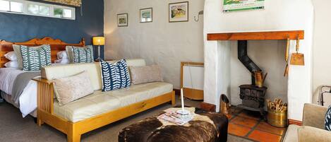 A cozy bedroom with a bed, a sofa, a wooden bench, and a fireplace.