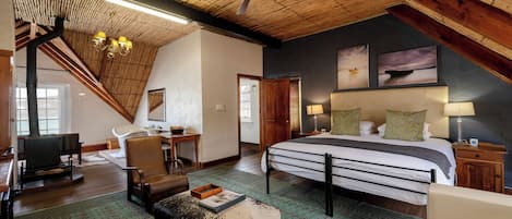 Ruime loft slaapkamer met een groot bed, houten plafond en uitzicht op de omgeving.