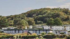 A building with multiple floors, surrounded by lush greenery and hills.