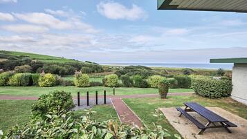 Enjoy a serene ocean view from this resort's tranquil outdoor space, featuring a lawn, gravel path, and picnic table.
