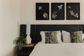 A neatly made bed with white linens, a dark green upholstered headboard, and two decorative pillows with intricate patterns. - Hotel Ponta Delgada (Ponta Delgada)