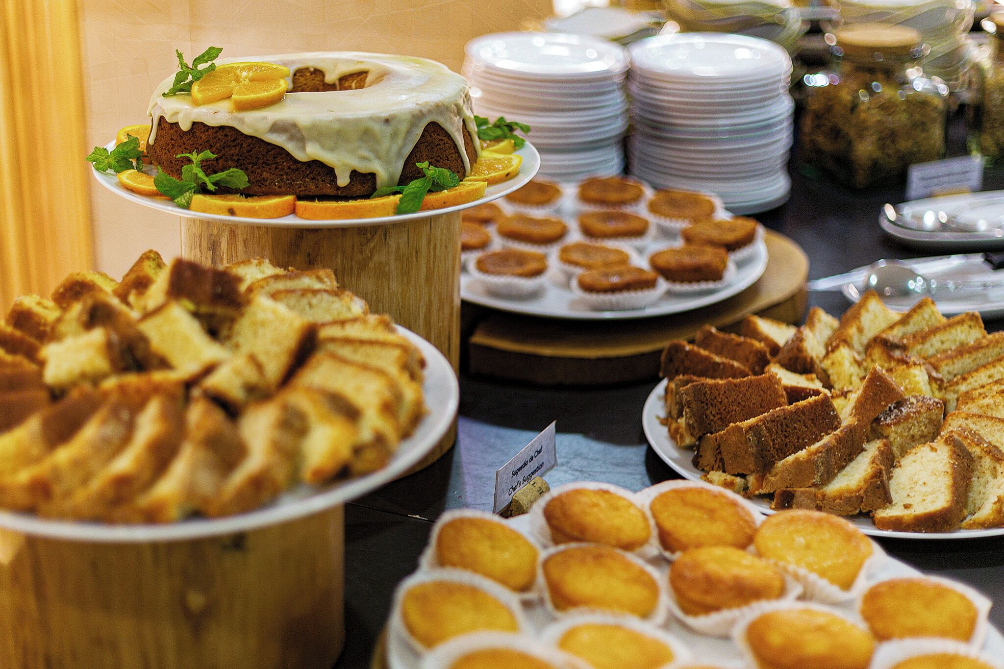 Een buffet met diverse etenswaren, waaronder een taart met witte glazuur, fruitschijfjes en verschillende soorten brood.