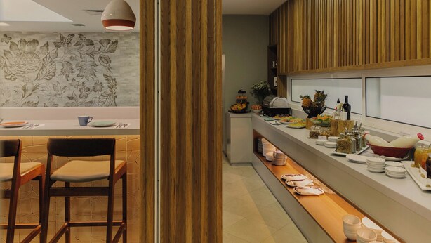Une cuisine moderne avec un coin repas, comprenant un buffet garni de divers plats et un mur décoratif orné d’un motif floral.