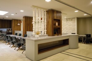 Un comptoir d’accueil au design moderne, agrémenté de panneaux en bois et d’une colonne décorative blanche.