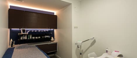 A bedroom with a bed, a vanity with a mirror, and a small table with a chair.