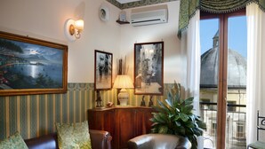 A living room with a sofa, armchairs, a lamp, a potted plant, and framed pictures on the wall. - Pinto Storey Hotel (Naples)
