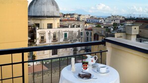 A balcony with a table set for tea, overlooking a historic town with colorful buildings and a prominent dome structure. - Pinto Storey Hotel (Naples)