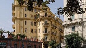 A multi-story building with balconies, a visible storefront, and a clear sky. - Pinto Storey Hotel (Naples)