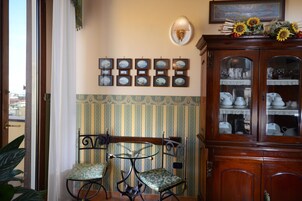 Una stanza con un armadio in legno, due sedie, un tavolo e una parete decorata con quadri.