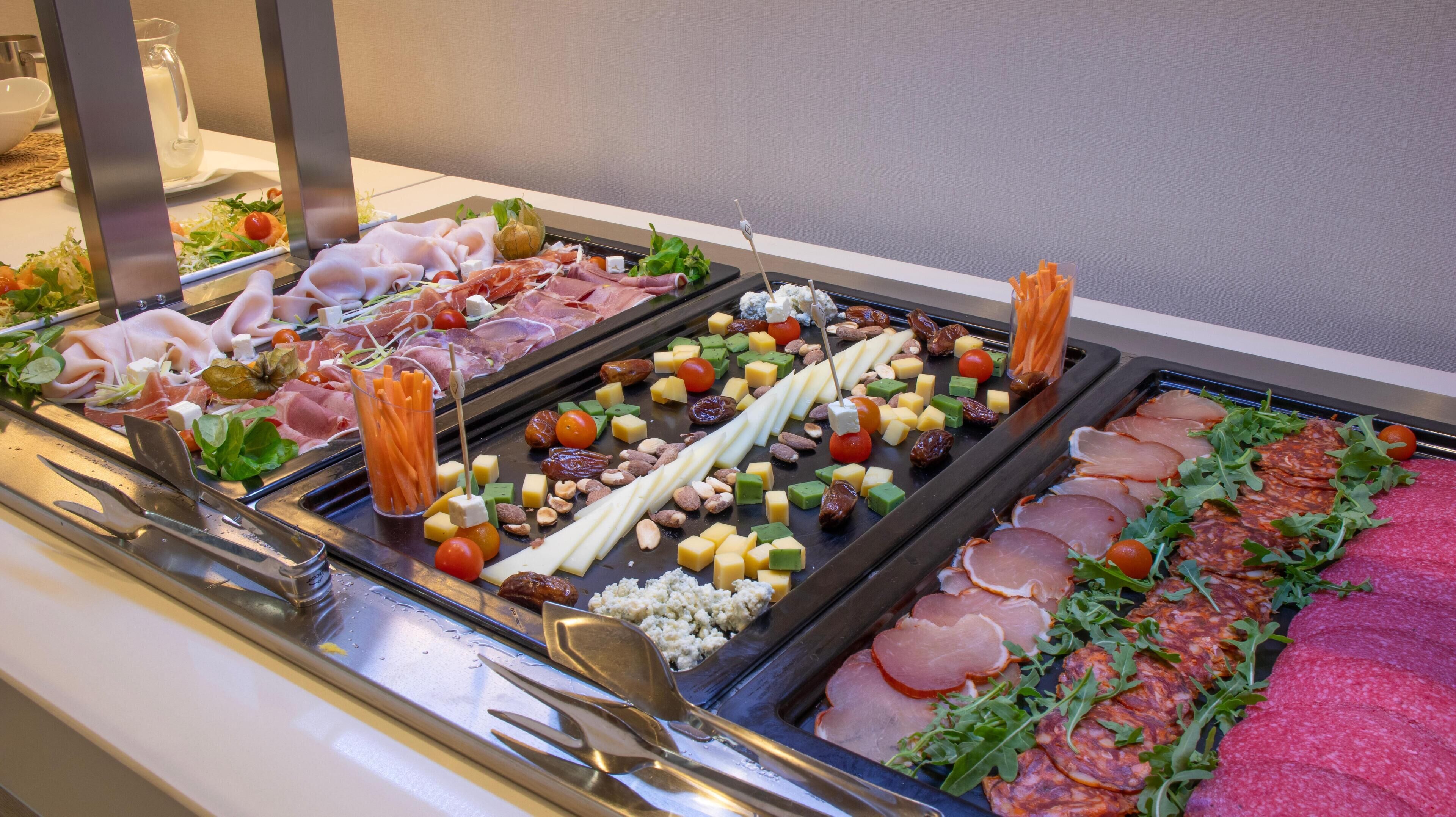 Un bufé con diversas carnes, quesos y verduras.