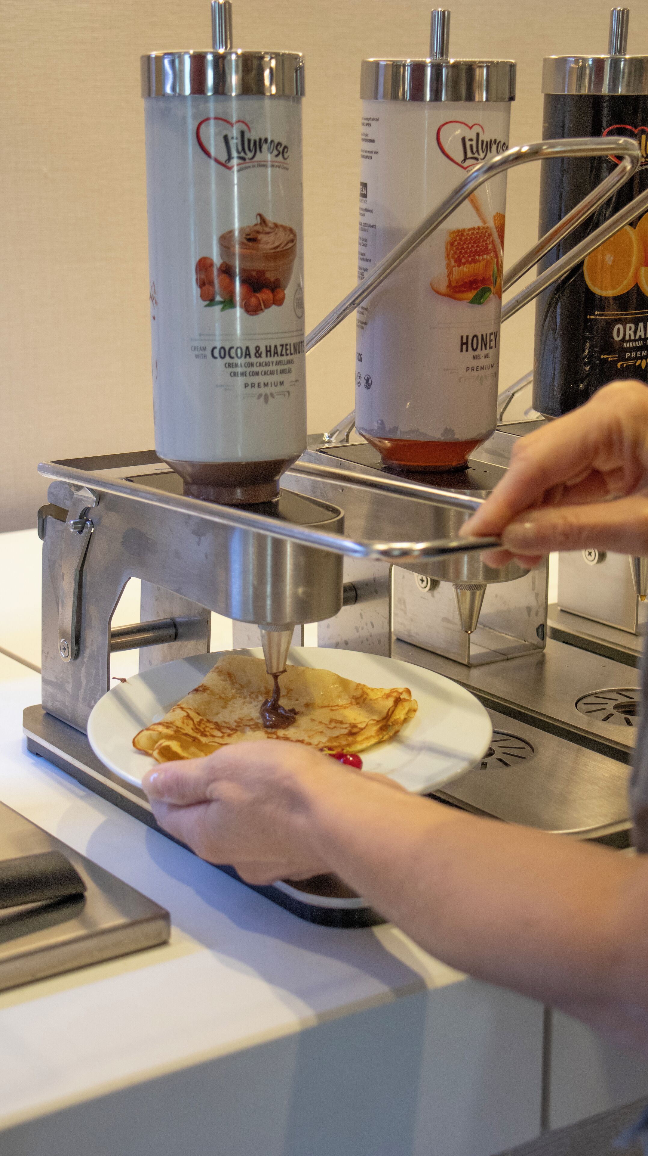 En person häller chokladsås från en behållare över en pannkaka.