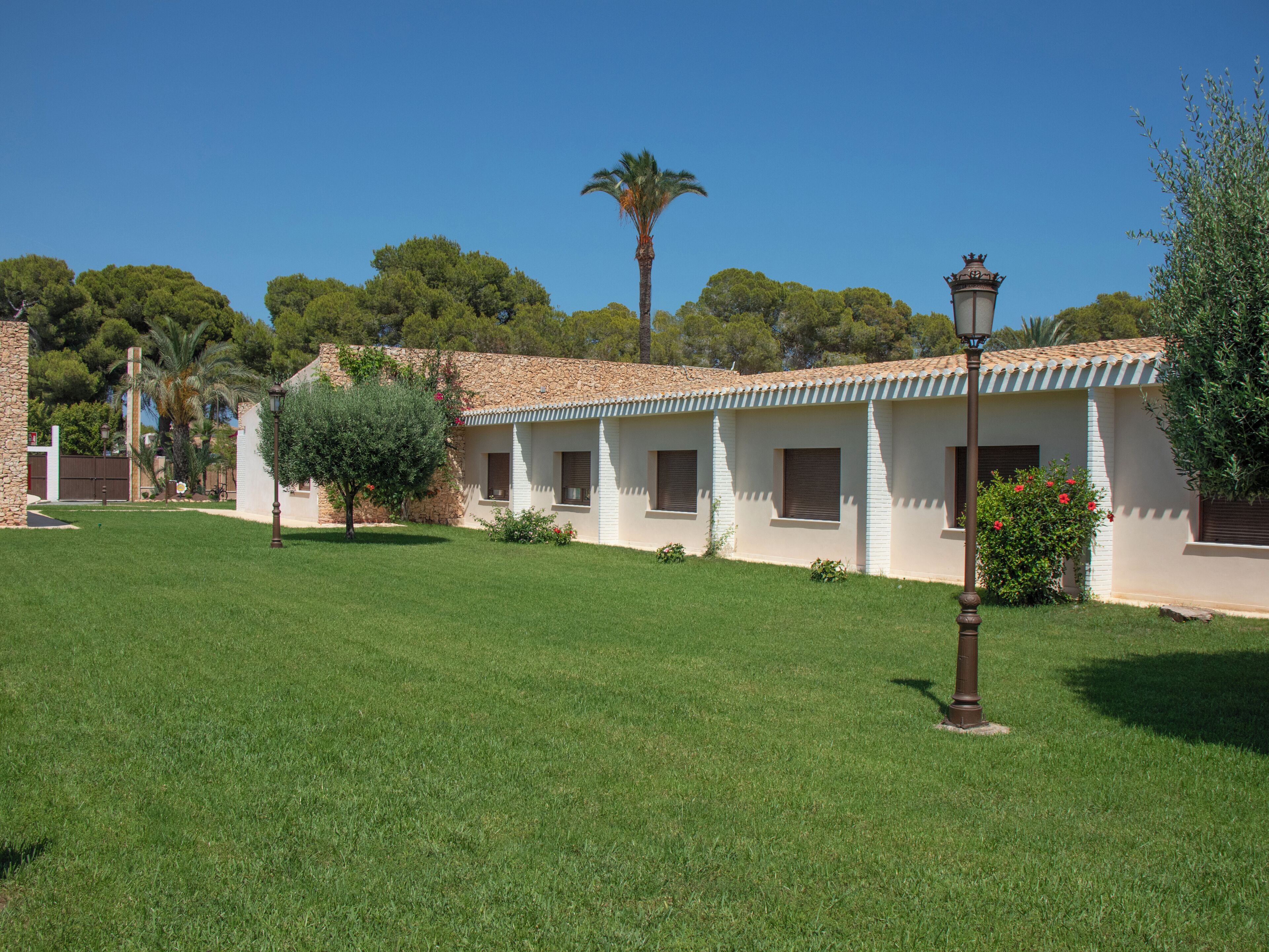 A building with a tiled roof, a stone wall, and a well-maintained lawn.