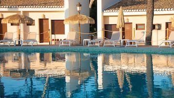 Een buitenzwembad, parasols bij het zwembad en ligstoelen