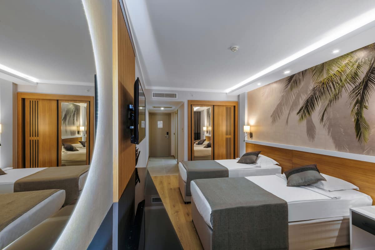 Ein Hotelzimmer mit zwei Einzelbetten, einem Schlafsofa, einem Fernseher und einer Wandmalerei.