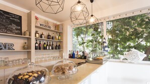 A bar area with a wine and liquor display, a welcome sign, and a view of greenery through the window. - Hotel Baia del Sole (Ragusa)