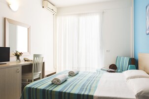 Una habitación de hotel con una cama, un escritorio con una silla, un televisor y una ventana con cortinas.